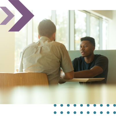 Corporate solicitor advising a client during a business discussion across a table.